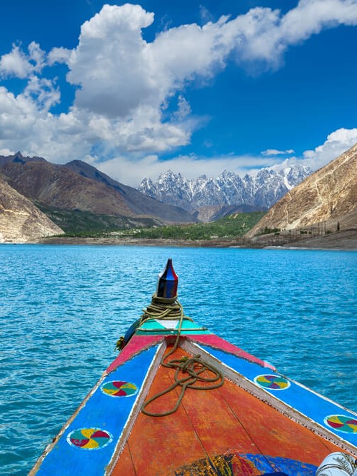 A colorful boat on Attabad Lake with mountains in the background