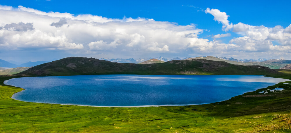 A scenic view of Sheosar Lake with hills and a cloudy sky